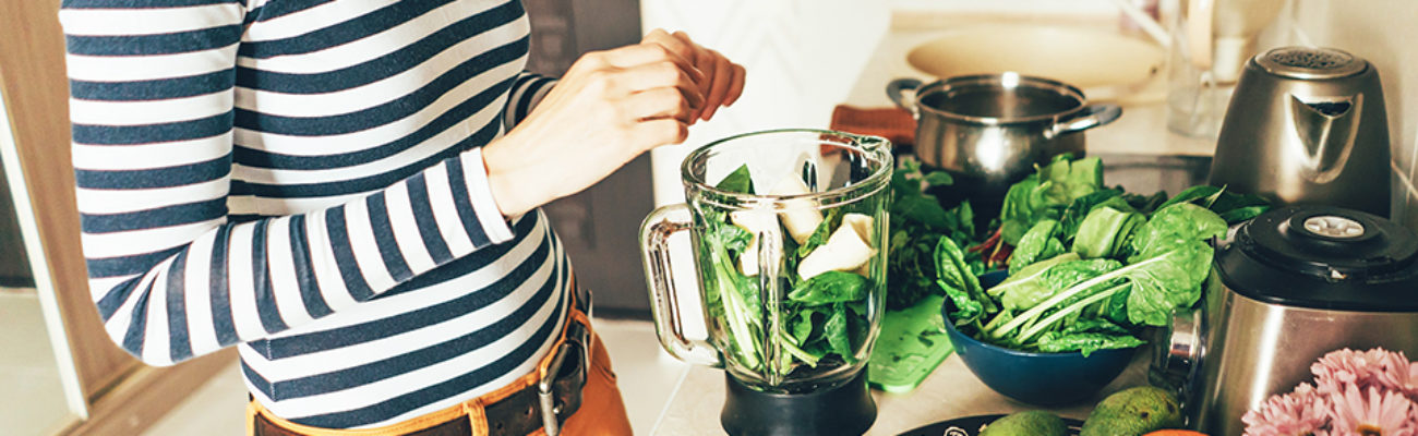 Woman in her kitchen preparing a smoothie.