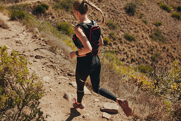 Woman running trail with hydration running vest