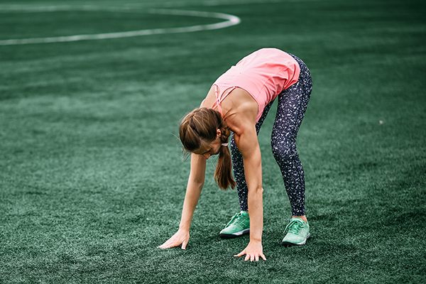 Woman doing burpees on grass field