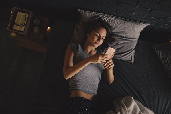 Woman checking phone in bed