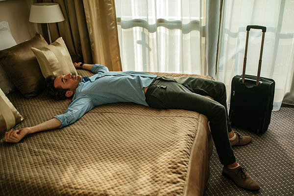 Tired man lying on the bed in a hotel room