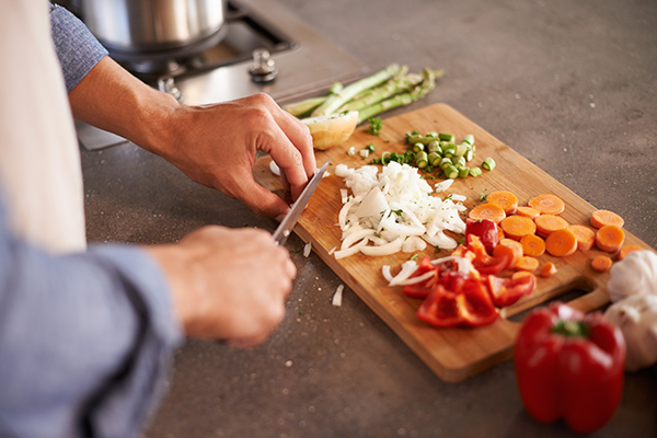 Man cutting vegetables on wood cutting board