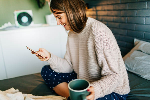 Woman sitting in bed drinking coffee