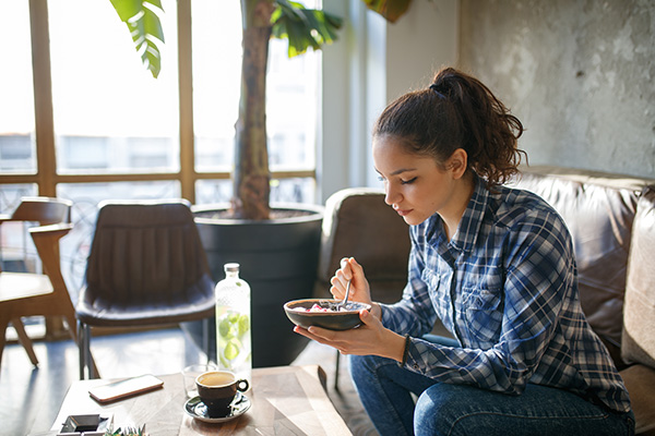 Woman eating bowl of yogurt and fruit