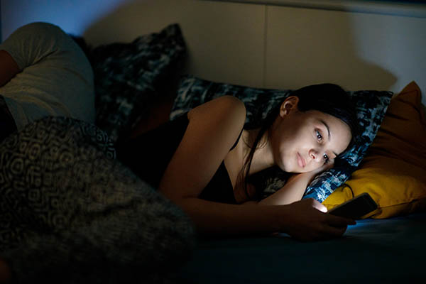 Woman looking at phone in bed