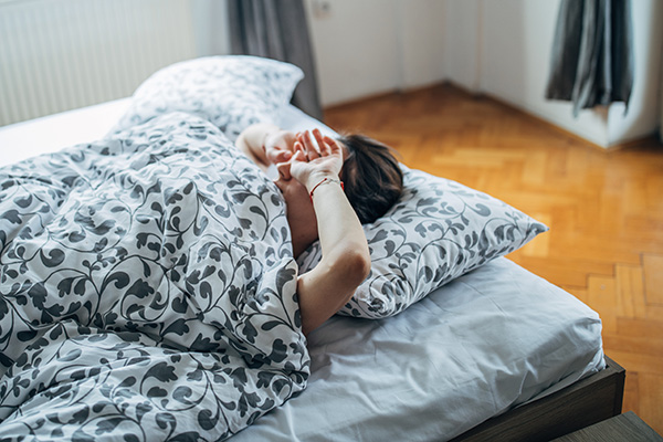 Young woman waking up in the morning and rubbing her eyes.