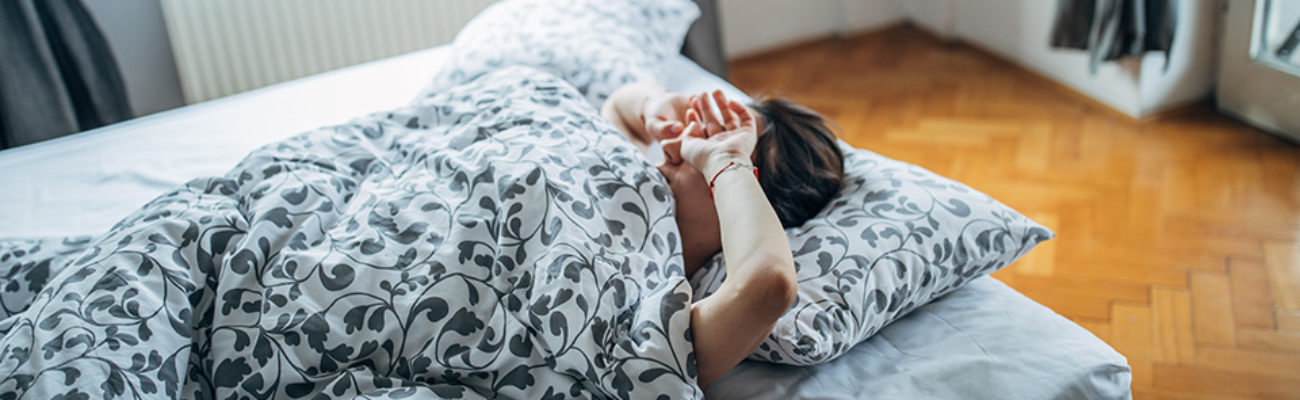 Young woman waking up in the morning and rubbing her eyes.