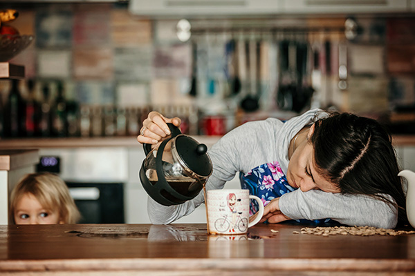 Tired mother, trying to pour coffee in the morning.