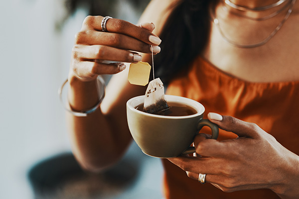 Woman holding tea cup, tea bag