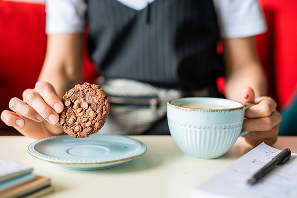 Woman eating a cookie with coffee