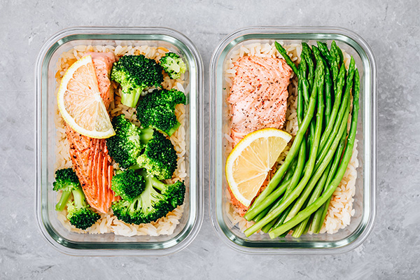 Meal prep lunch box containers with salmon, rice, broccoli, asparagus.