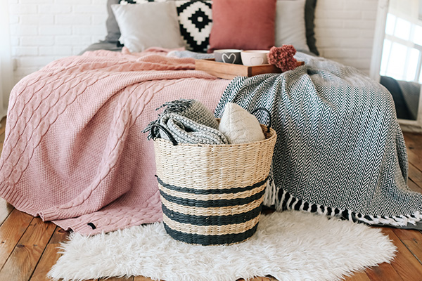 Blankets on bed, pillows in basket