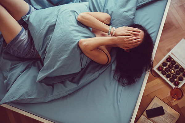 Stressed woman in bed with chocolate and wine