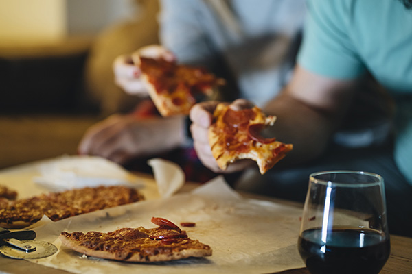 Couple eating pizza on the sofa in their living room