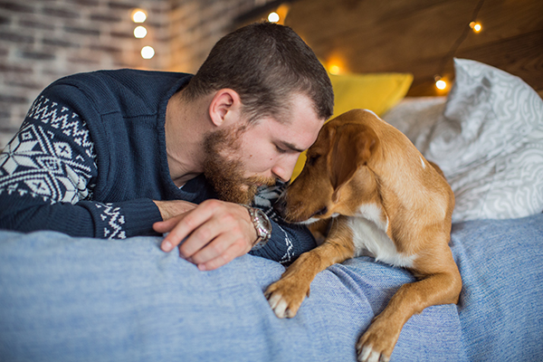 Young man laying on the bed with his dog.