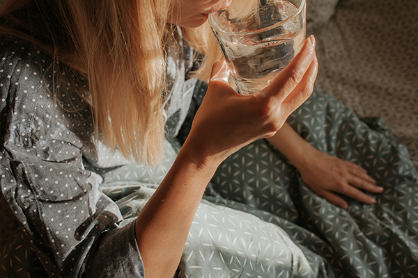 Woman drinking water sitting in bed