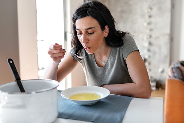 Young woman eating bone broth.