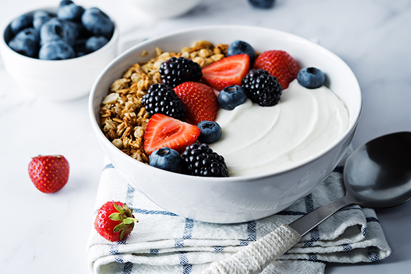 Greek yogurt, nuts, granola, berries in a bowl.