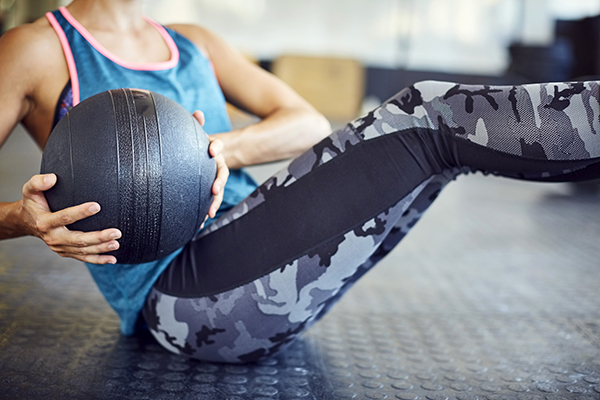 Woman doing Russian Twist a with medicine ball in gym.