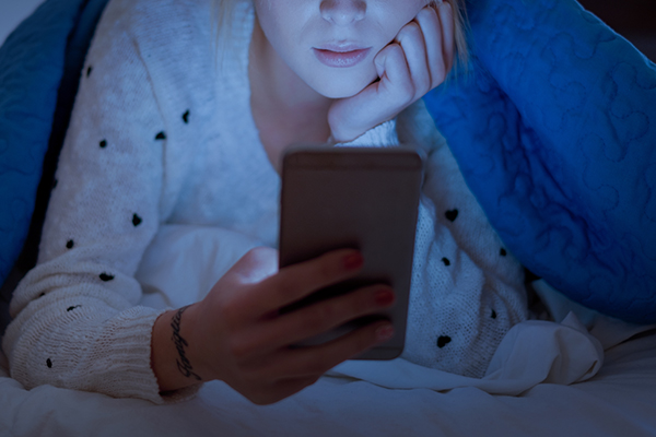 Woman looking at her cellphone in bed