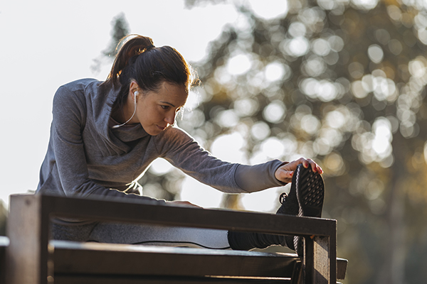 Young woman stretching leg in park.