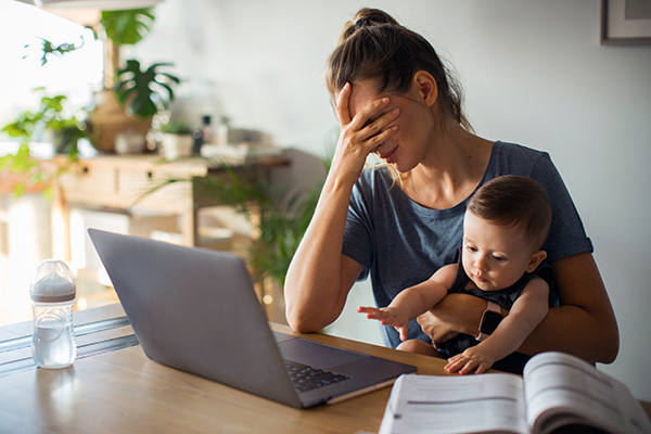 Tired mom sitting in front of computer with baby.