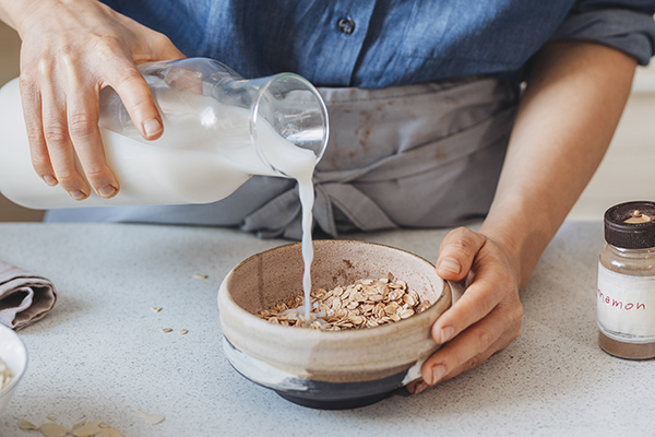 Woman preparing oatmeal with almond milk