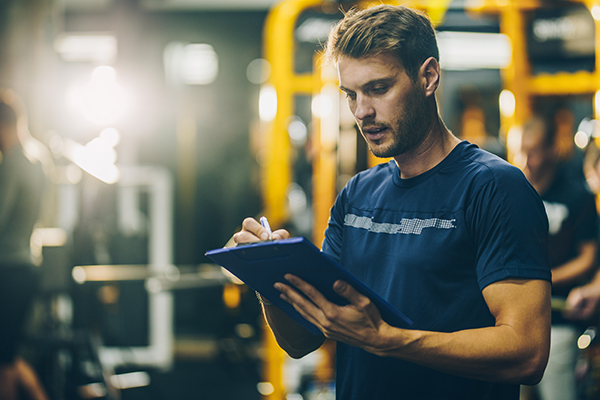 Man writing in fitness journal at gym