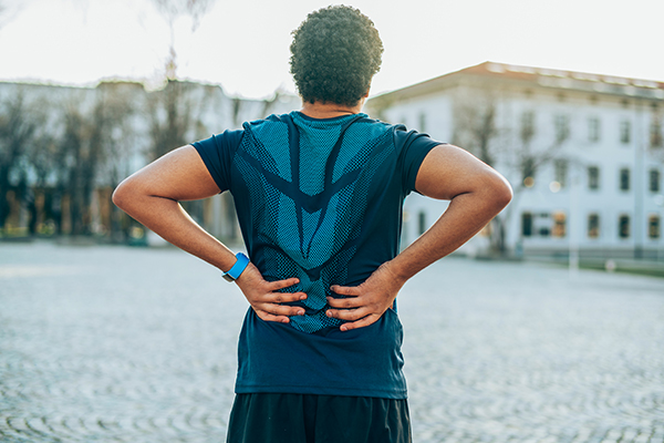 Man rubbing muscles of lower back after jogging