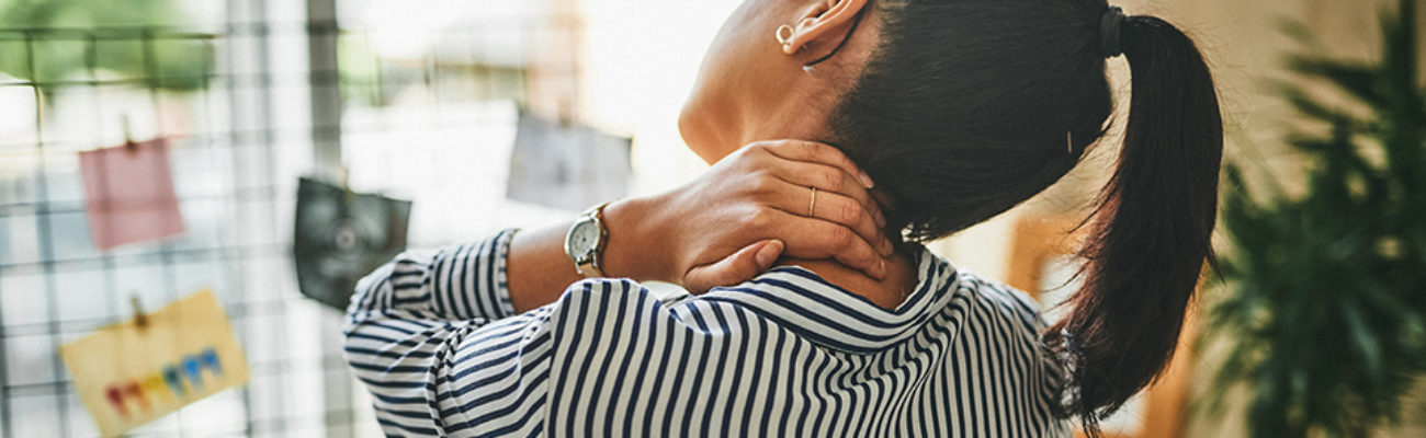 Woman rubbing her neck while working from home