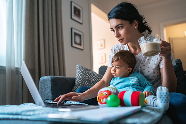 Mother with a baby using laptop at home.