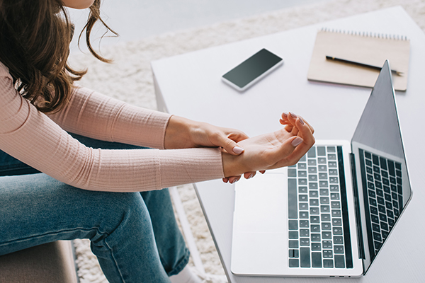 woman having pain in wrist while using laptop