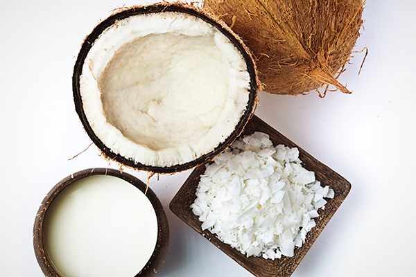 Top view of opened coconut, coconut milk, and shredded coconut
