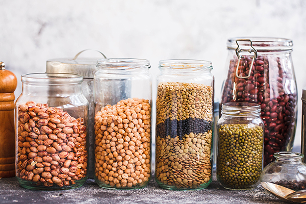 Lentils, peas, soybeans and red beans in glass jars.