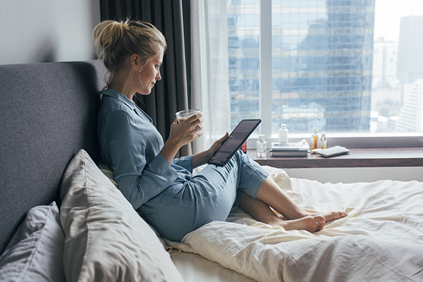 Woman relaxing in bed looking at her tablet