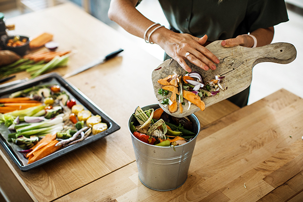 Woman putting vegetable scraps in compost pail