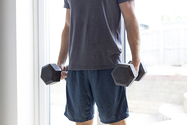 Shot of a man lifting weights at home