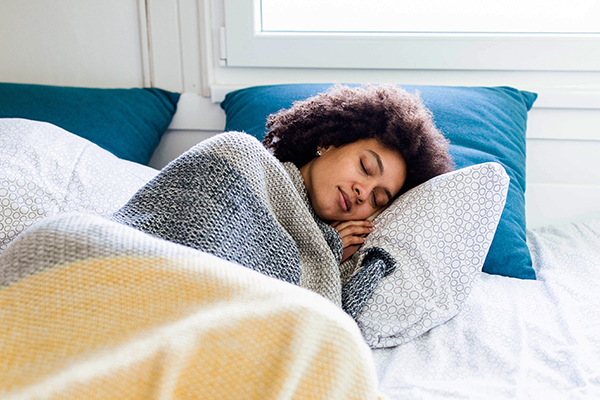 Woman sleeping in bed under blankets