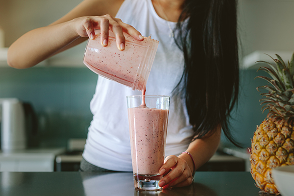 Woman pouring Shakeology smoothie into a glass