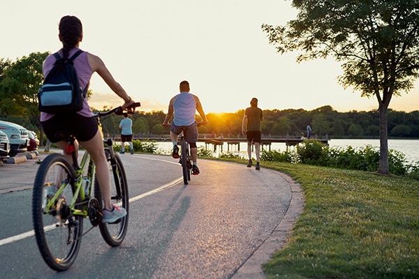 Bikers and runners on a trail at sunset.