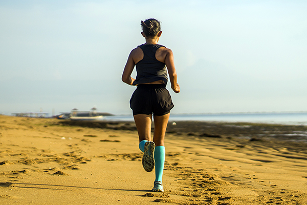 Woman running on beach wearing compression socks