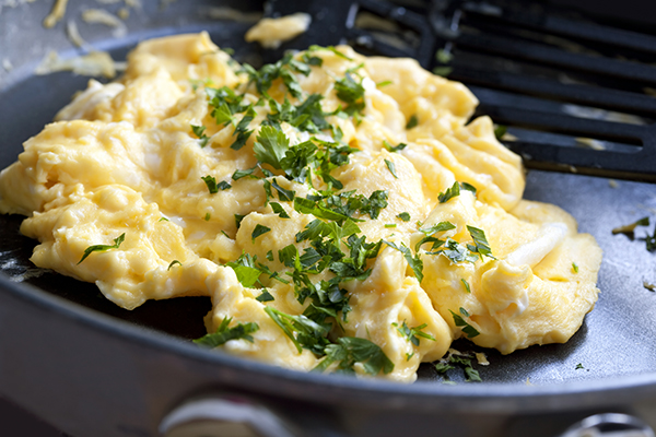 Scrambled eggs cooking in a frypan, with spatula. 