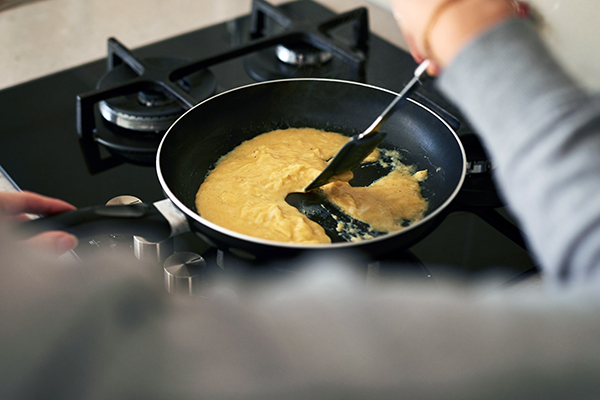 Person stirring scrambled eggs in pan