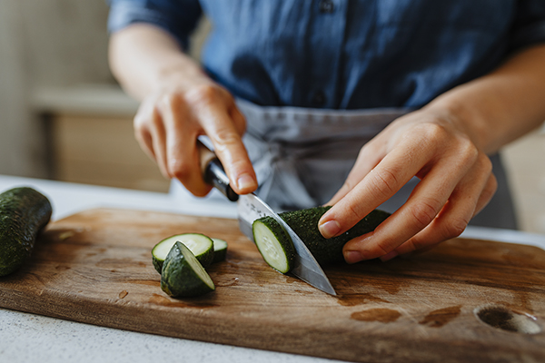 Woman slicing a cucumber on cutting board