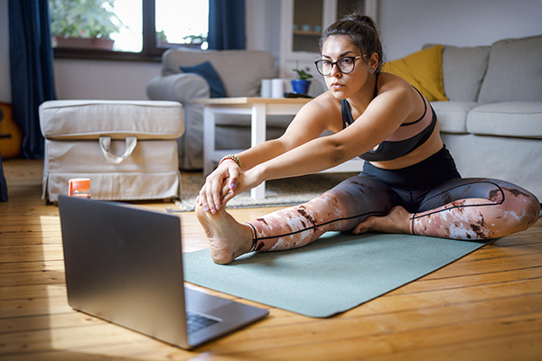 Woman stretching on yoga mat at home