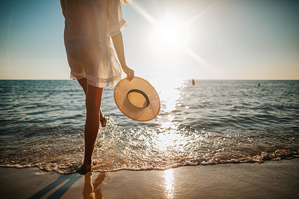 Shot of woman standing on the beach with sun hat