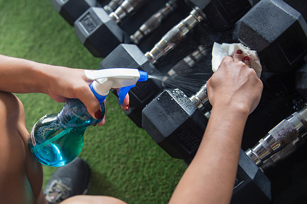 Woman cleaning dumbbells with cleaning spray