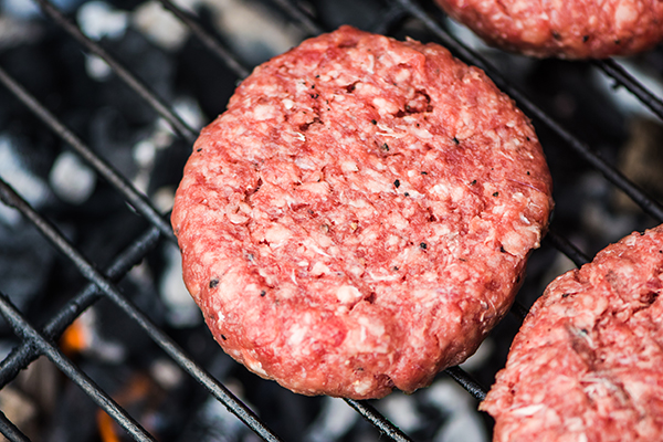 Raw burgers cooking on a grill