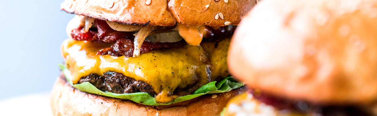 Two freshly grilled burgers on buns with toppings