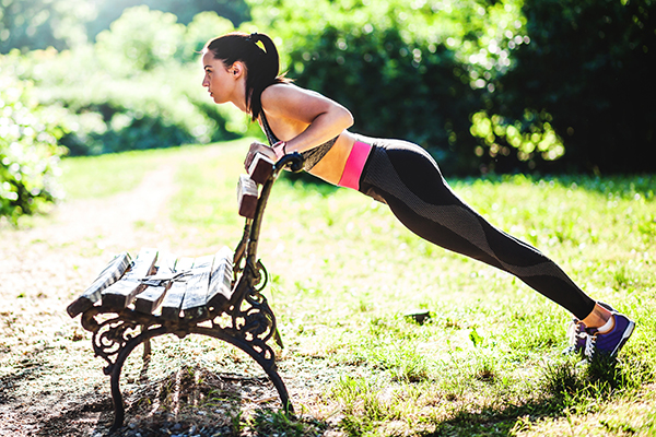Woman doing incline push-up on park bench